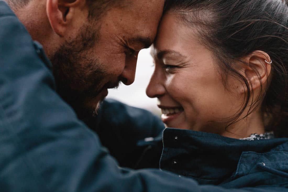 A smiling couple touches foreheads and embraces.