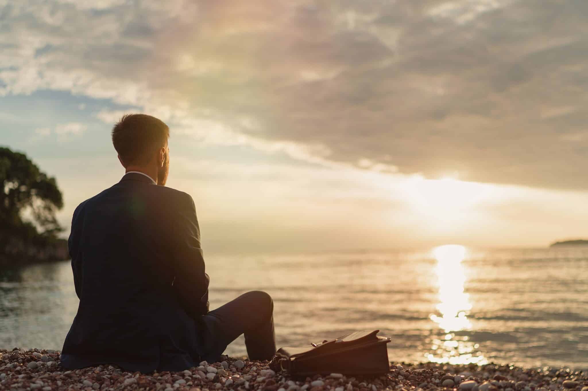 Man sitting on beach at sunset