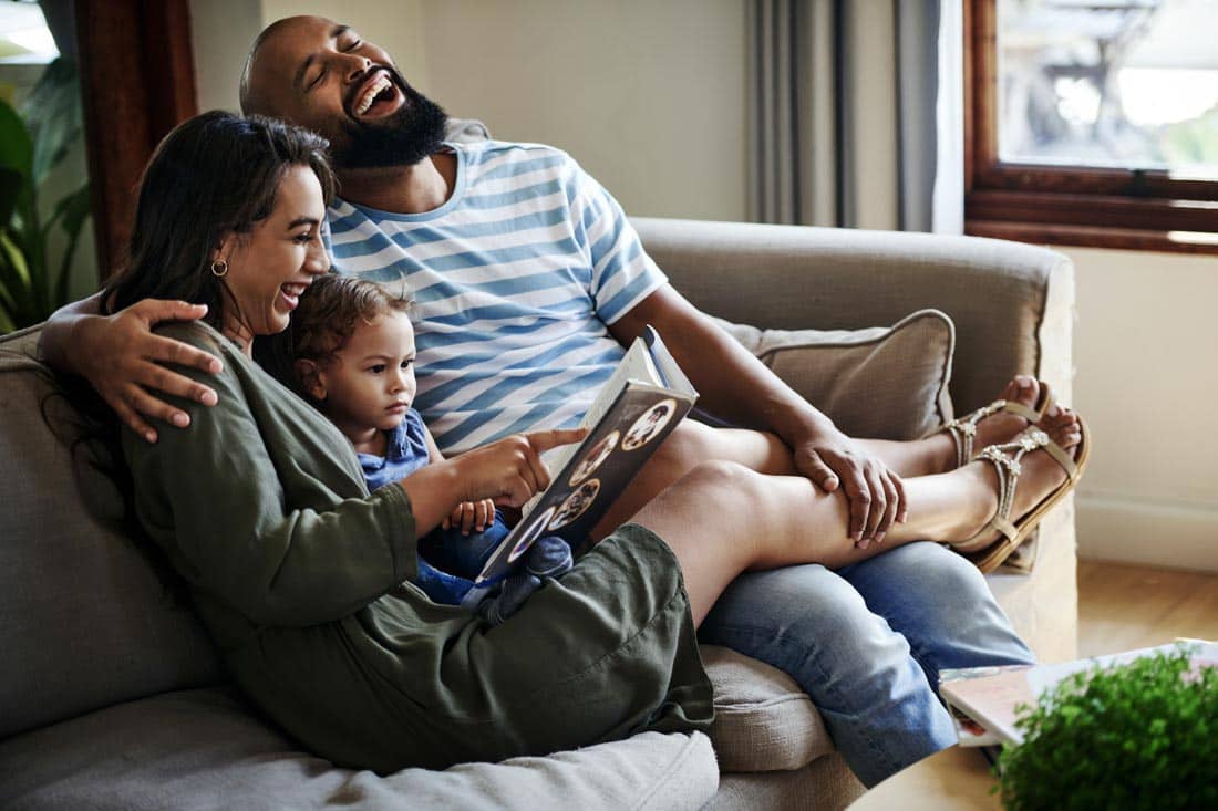 Couple reading a book to their child.