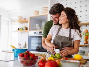 Happy couple laughing while cooking a meal together.