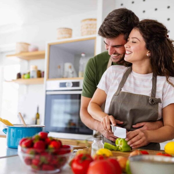 Happy couple laughing while cooking a meal together.
