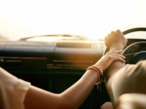 Attached young couple touching hands in car.