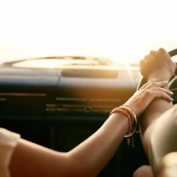 Attached young couple touching hands in car.