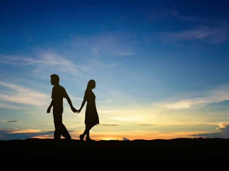Couple walking away from each other at sunset.