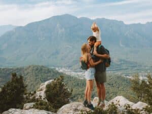 Close couple kissing with their baby on a mountain top.