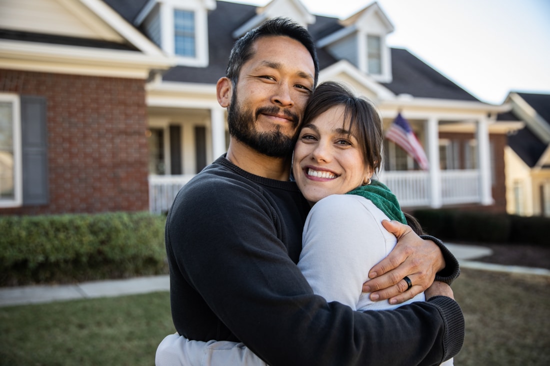 Husband and wife embracing in front of home