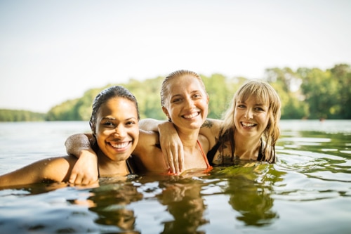 Photo of three happy female friends enjoying the lake, representing advice for creating positive relationships and empowered connections.