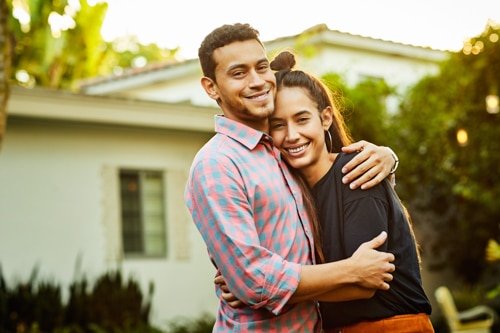 Photo of a happy couple embracing in front of their home, representing relationship advice for growing together.