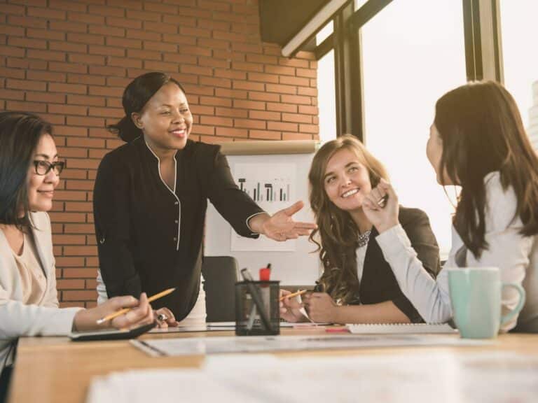 Managing up for career success, group of coworkers gathers around a table to discuss new ideas