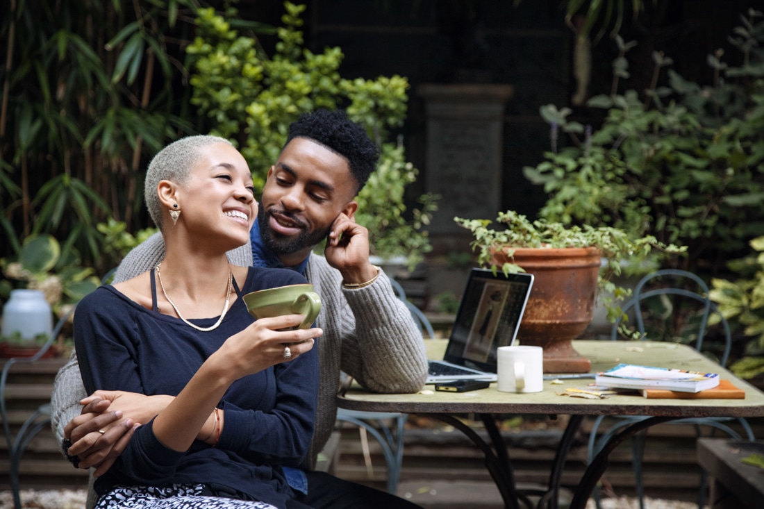 Happy woman holding coffee cup while talking with boyfriend, representing online couples counseling.