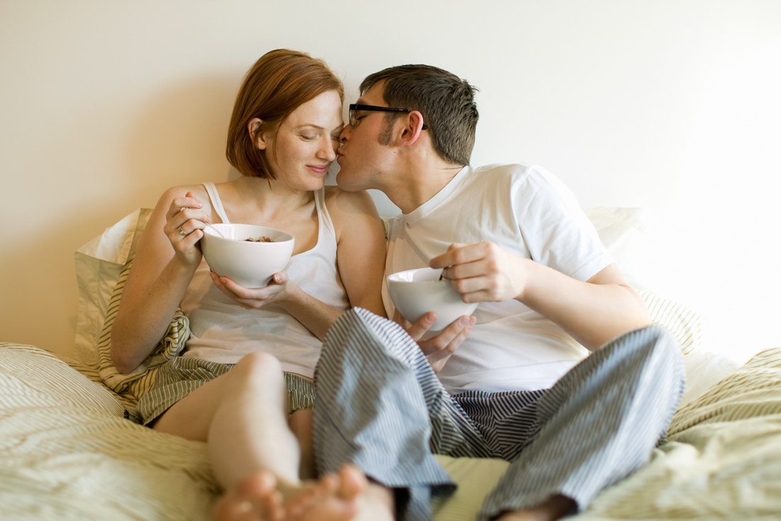 couple eating breakfast together in bed, being affectionate