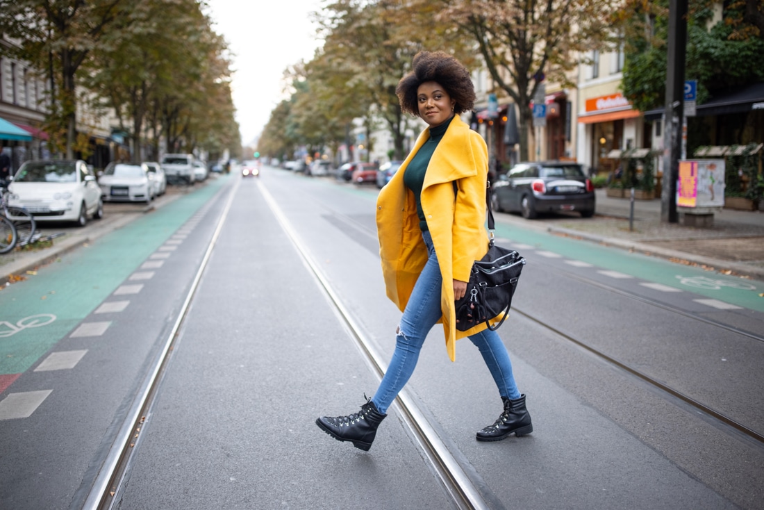 Confident, happy African American woman walking across a city street: create meaningful change