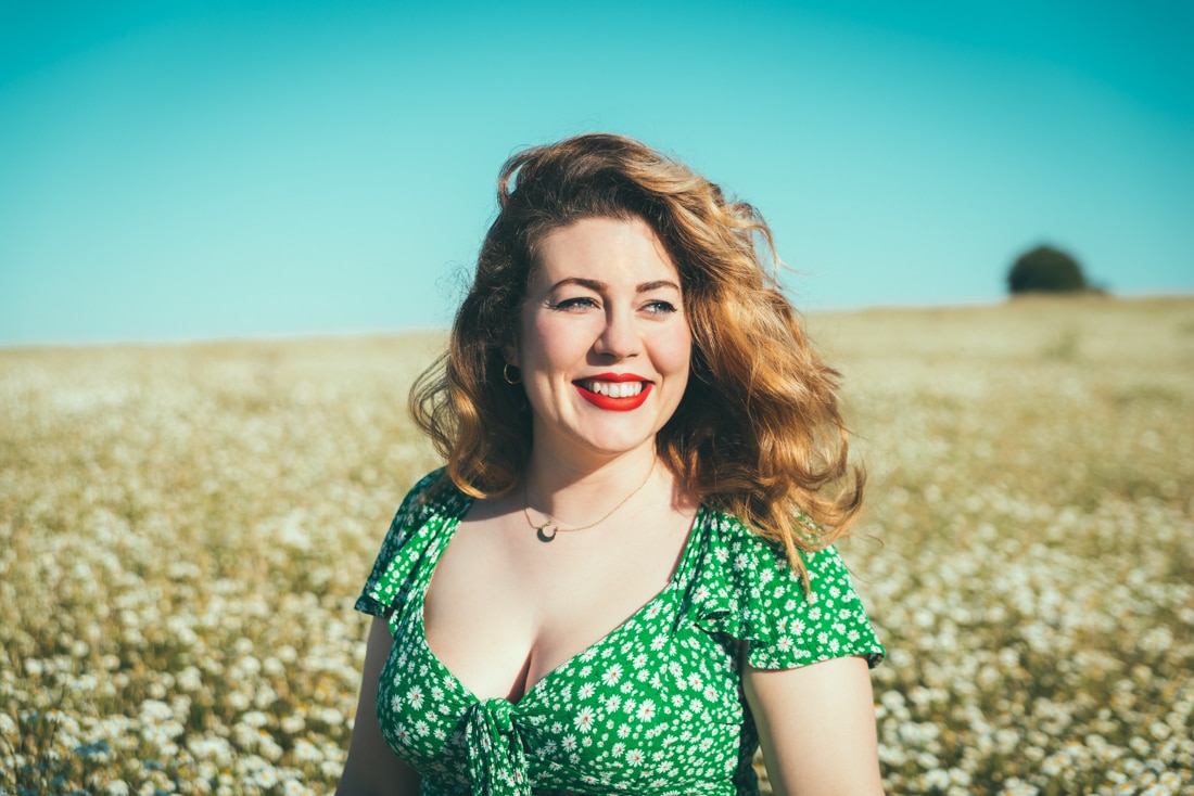 young woman smiling in a field, therapy and coaching for personal growth