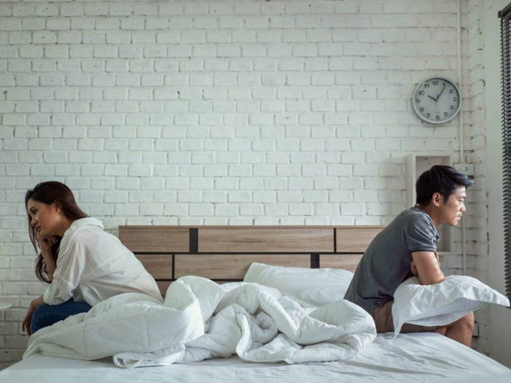 asian couple sitting on opposite sides of bed upset - so you cheated, now what