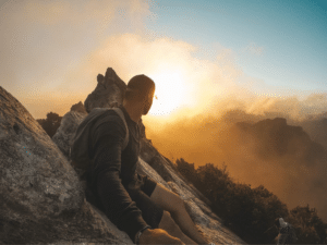 Man making it to the top of mountain representing the nature of resilience