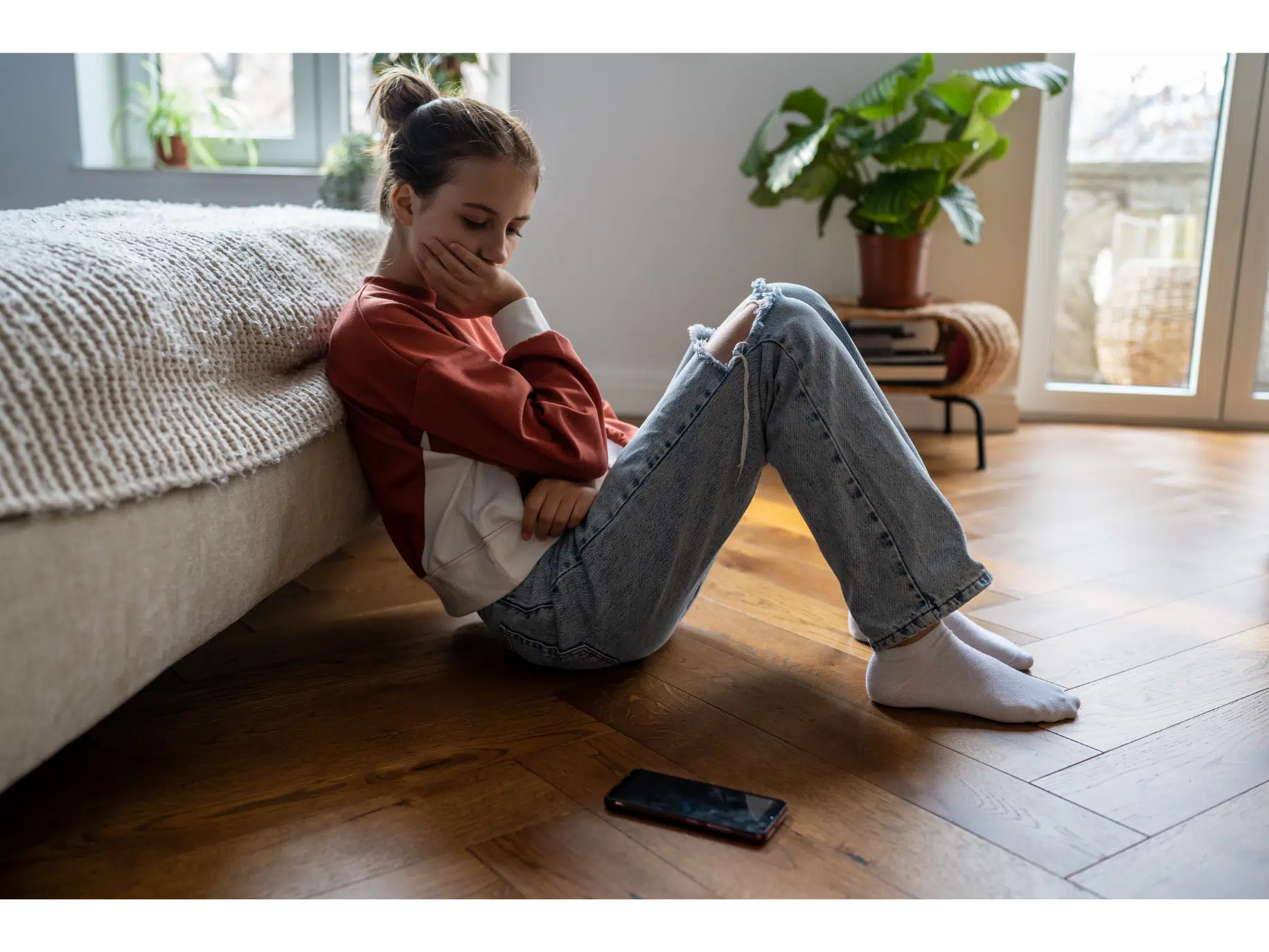 A woman sitting on the floor looking at her phone representing not knowing how to get closure