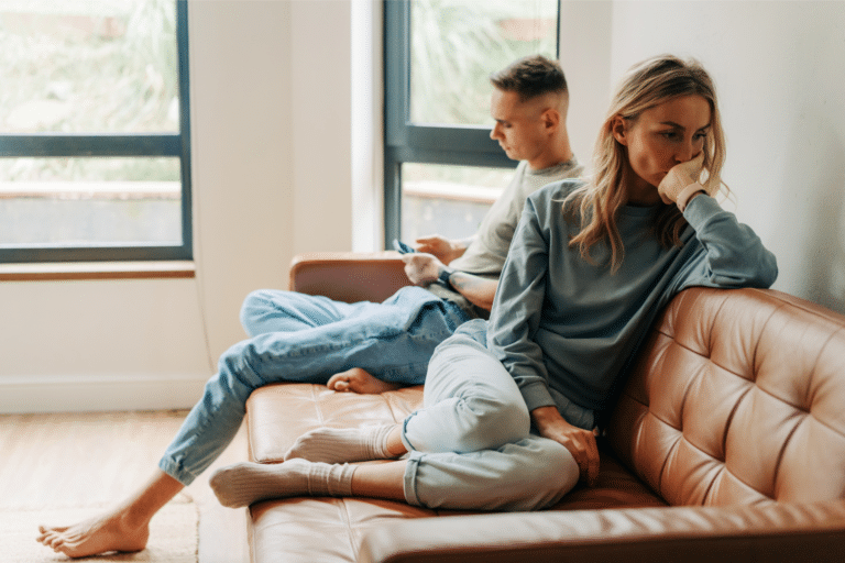 A couple sits on the couch looking unhappy representing what does it mean to be emotionally unavailable