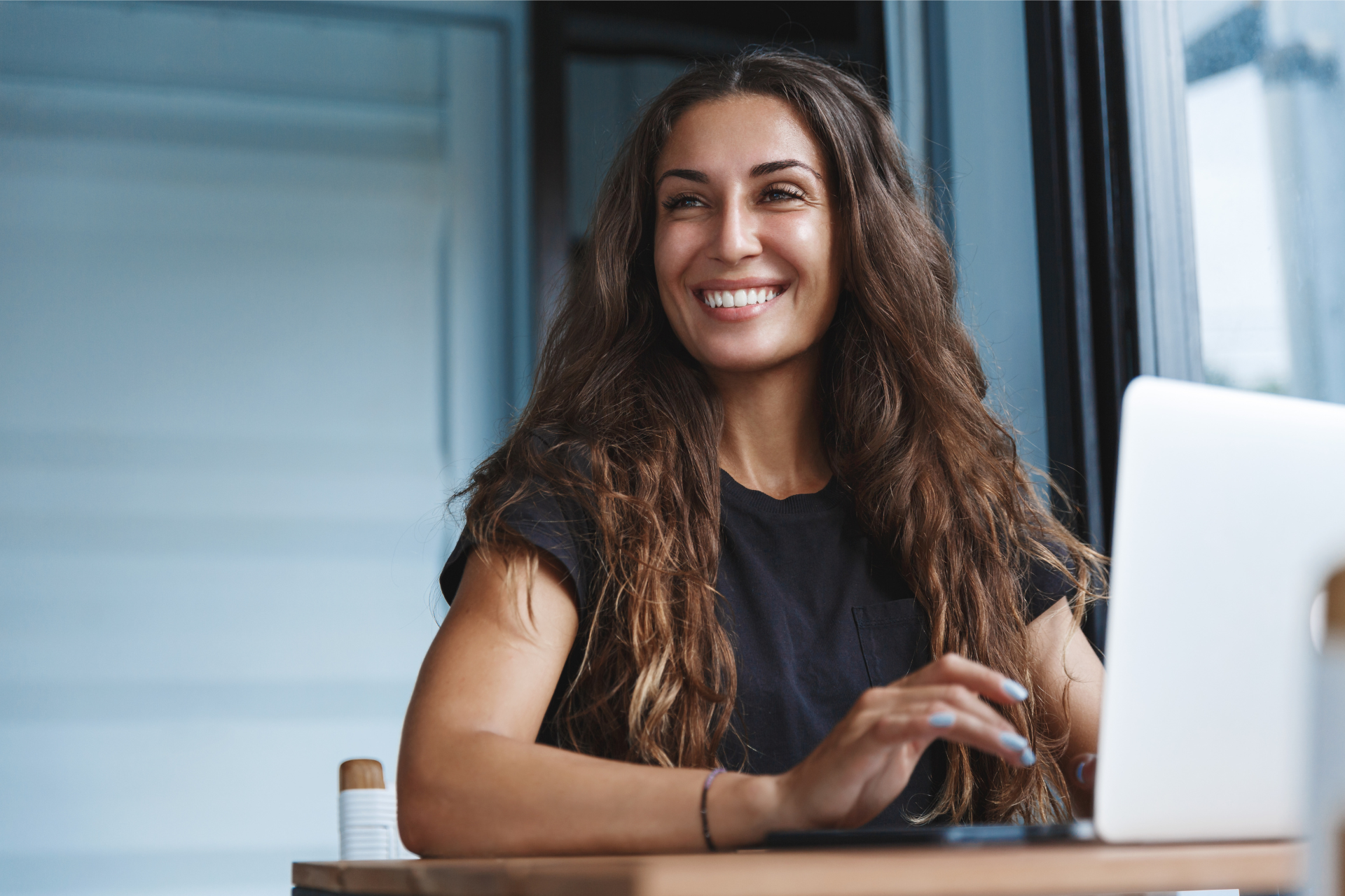 A woman sits at her laptop looking happy representing how to get out of your own way