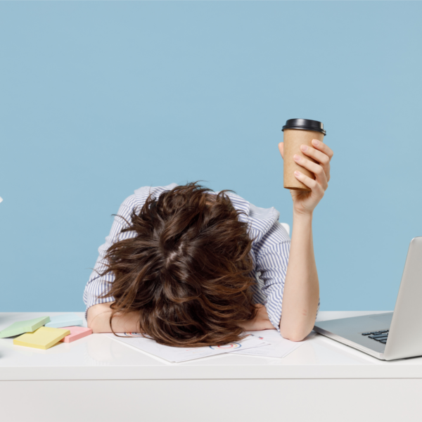 An overwhelmed woman puts her head down on her desk representing setting boundaries at work