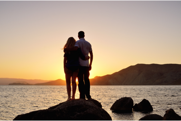 A couple stands by the ocean looking at the sunset representing tools for surviving infidelity