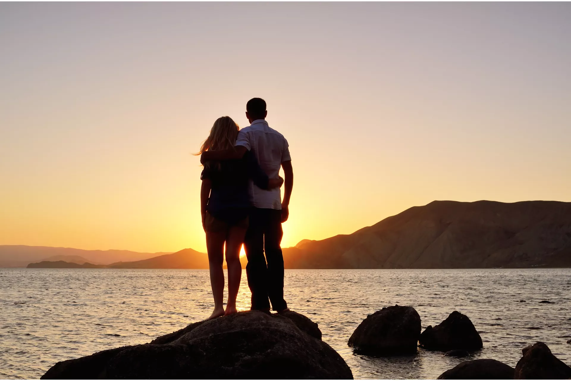 A couple stands by the ocean looking at the sunset representing tools for surviving infidelity