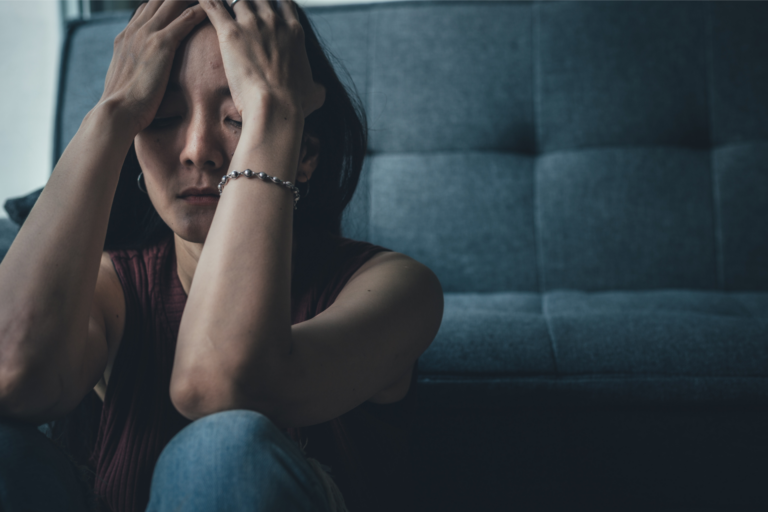 A woman cradles her head representing how to stop ruminating