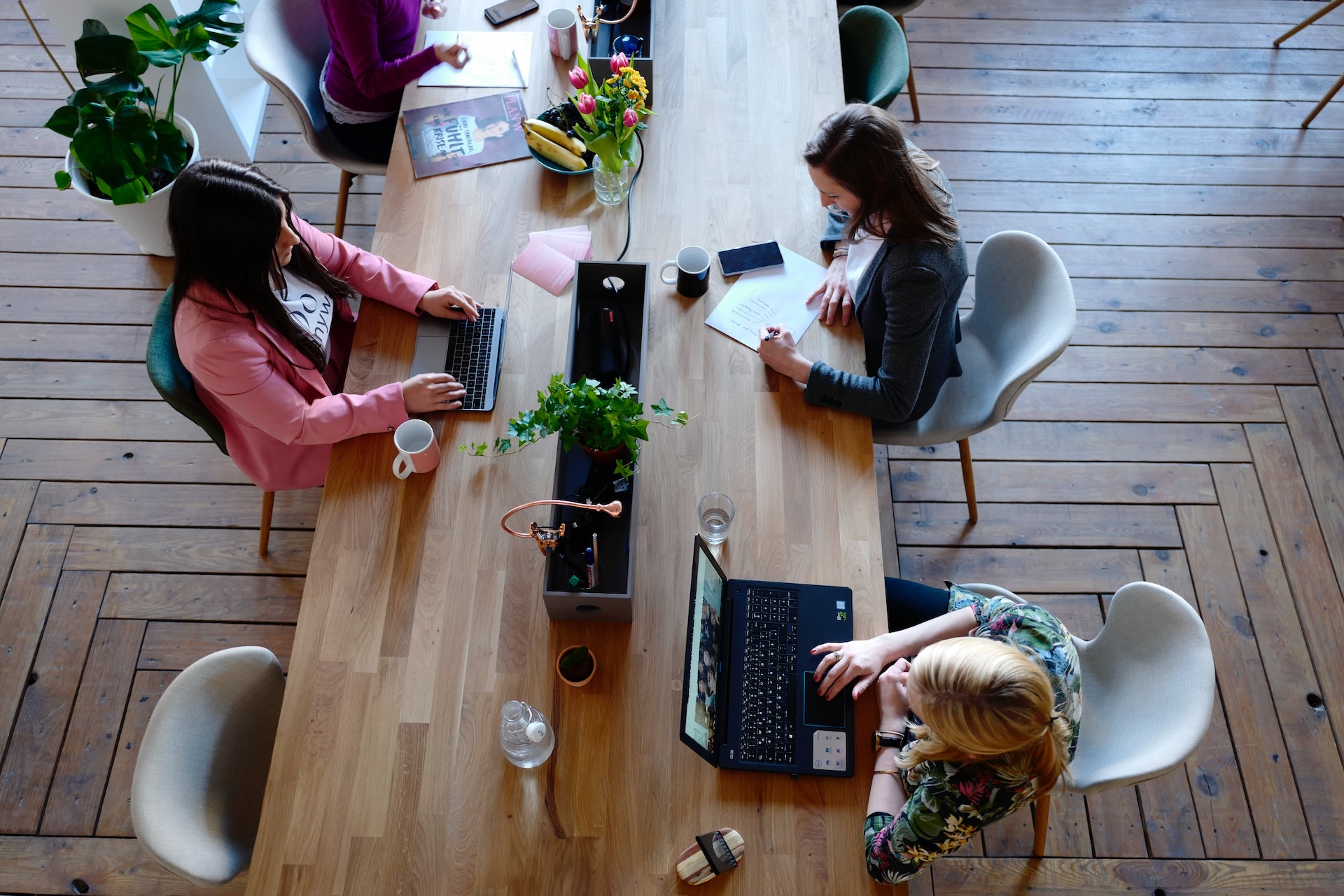 A group of people productively work at a large table representing the 90 20 Rule.