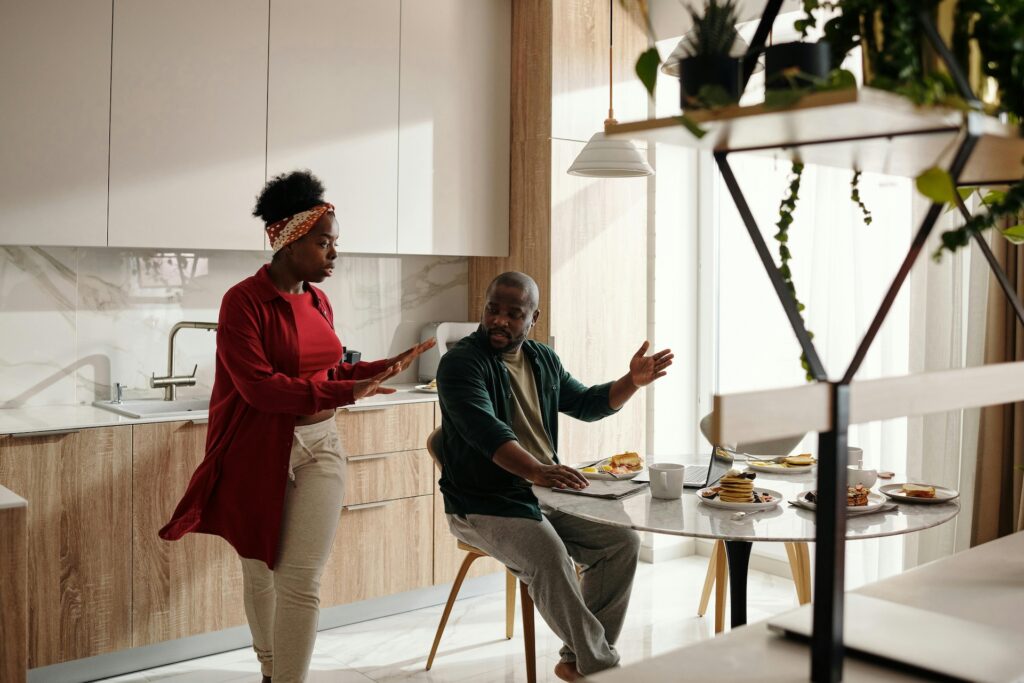 A woman and a man argue in the kitchen representing setting boundaries vs. ultimatums.