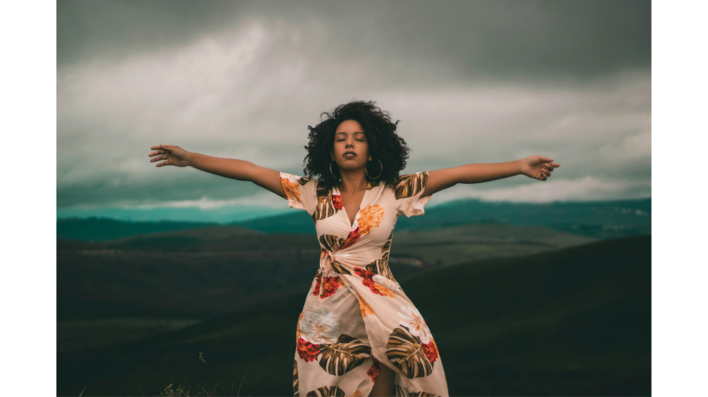 A woman stands holding out her arms in a storm representing how to silence your inner critic