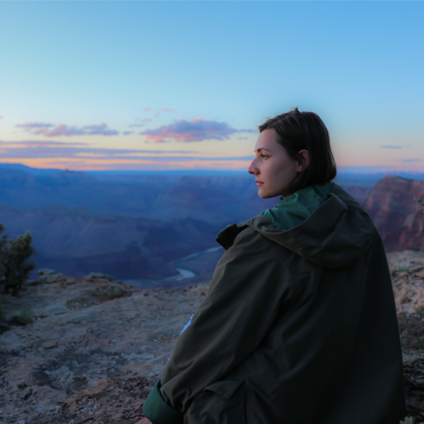 A woman sits at the edge of a canyon enjoying the sunset representing how to simplify your life