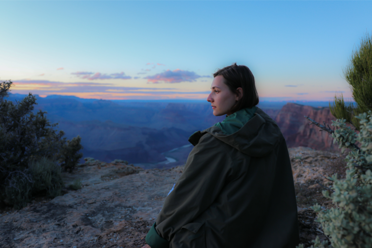 A woman sits at the edge of a canyon enjoying the sunset representing how to simplify your life