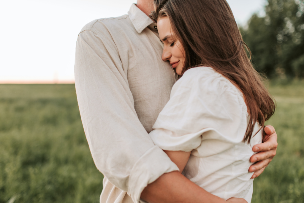 A man and a woman hug in a field representing relationship myths that keep you single