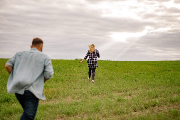 A man chases a woman through a field representing the pursuer-withdrawer cycle in relationships.
