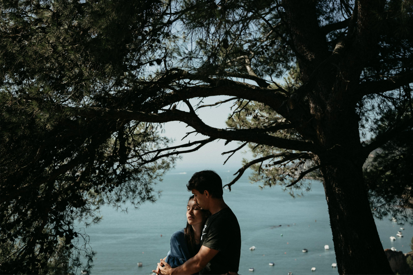 A couple shares a hug under some trees in front of the sea representing how to forgive your partner