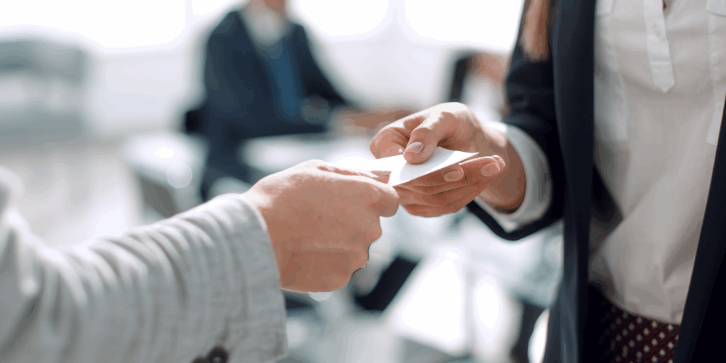 A therapy client hands their friend their therapist's business card representing Ethical Dilemmas: When Therapy Clients Refer Their Friends
