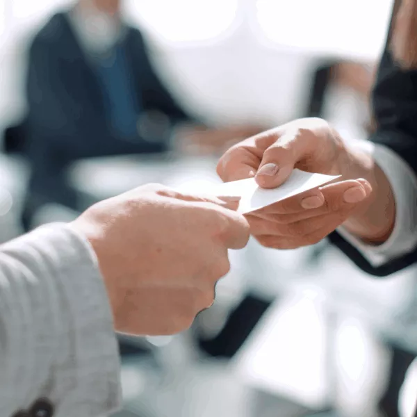 A therapy client hands their friend their therapist's business card representing Ethical Dilemmas: When Therapy Clients Refer Their Friends