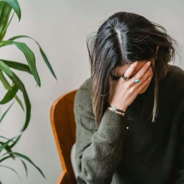 A therapist sits with her head in her hands representing Too Close to Home - Navigating Personal Challenges as a Therapist
