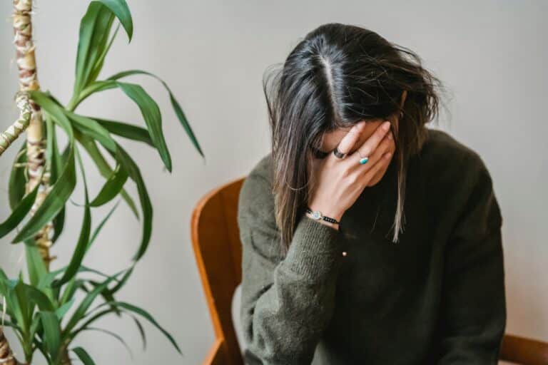 A therapist sits with her head in her hands representing Too Close to Home - Navigating Personal Challenges as a Therapist