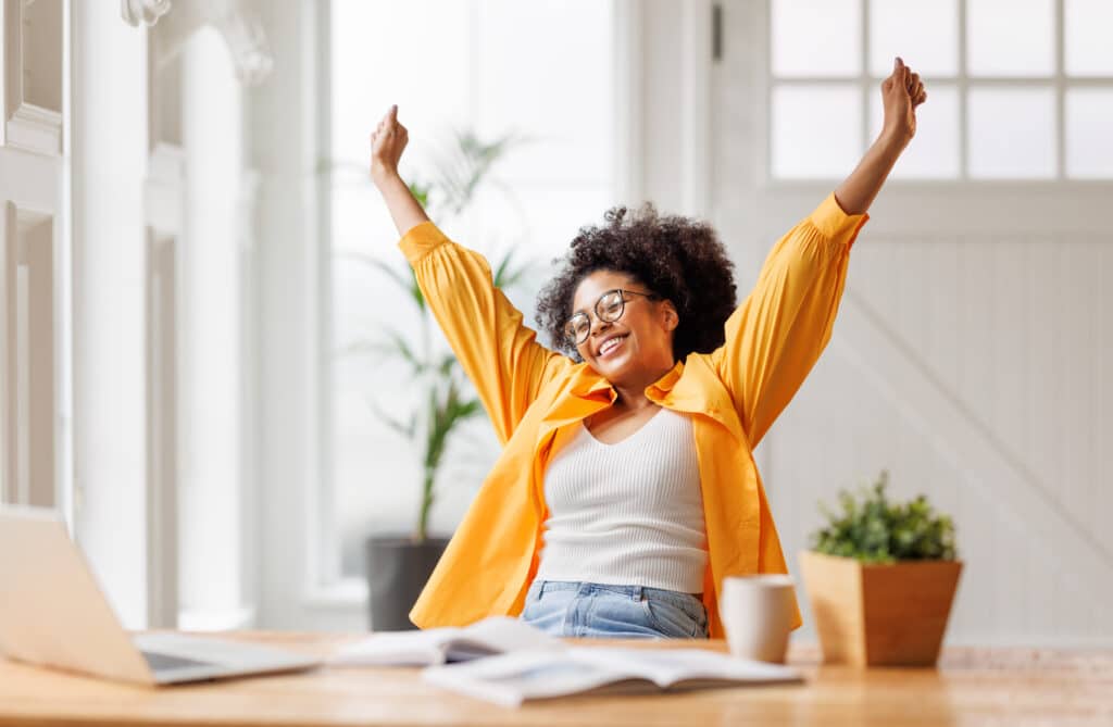 A woman celebrates after achieving her goal representing how to reprogram your subconscious mind, break patterns, and crush your goals.