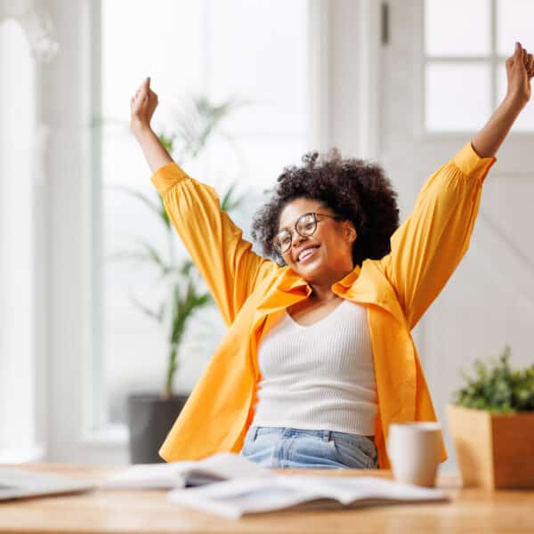 A woman celebrates after achieving her goal representing how to reprogram your subconscious mind, break patterns, and crush your goals.