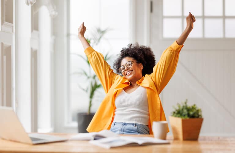 A woman celebrates after achieving her goal representing how to reprogram your subconscious mind, break patterns, and crush your goals.