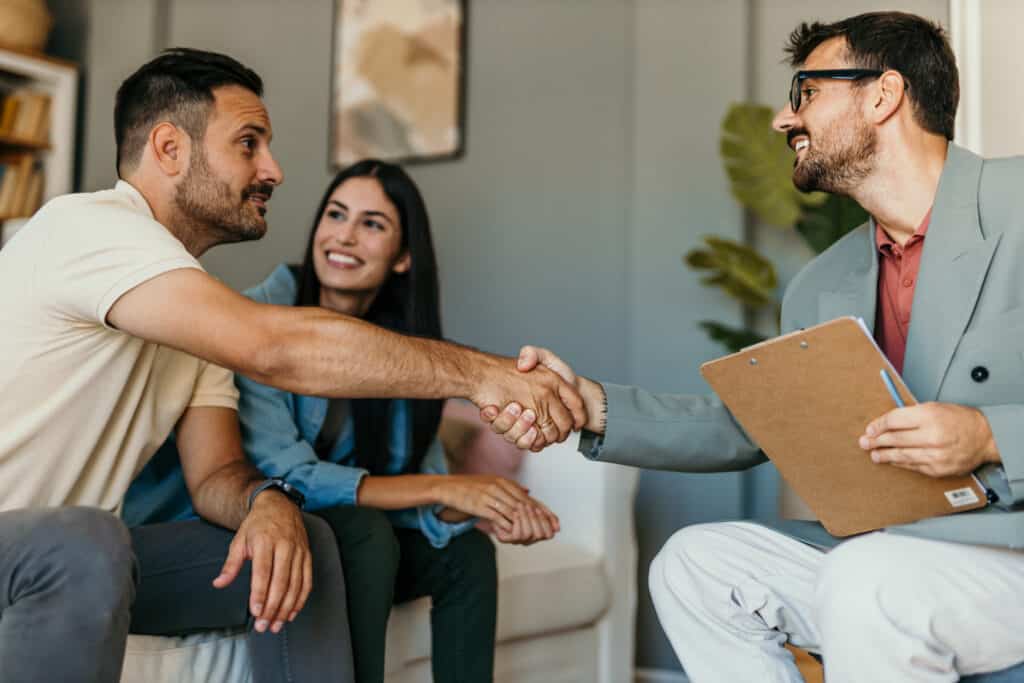 A couples therapist greats his enthusiastic clients representing Secrets to Therapy Client Engagement.
