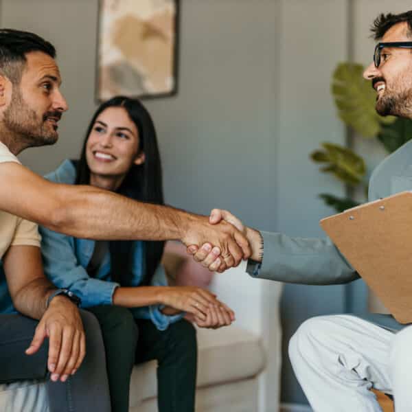 A couples therapist greats his enthusiastic clients representing Secrets to Therapy Client Engagement.