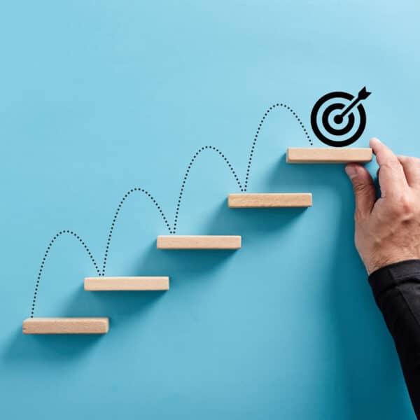 Wooden steps ascending with a target at the top representing Settings Goals for a Life and Career You Love as a Therapist.
