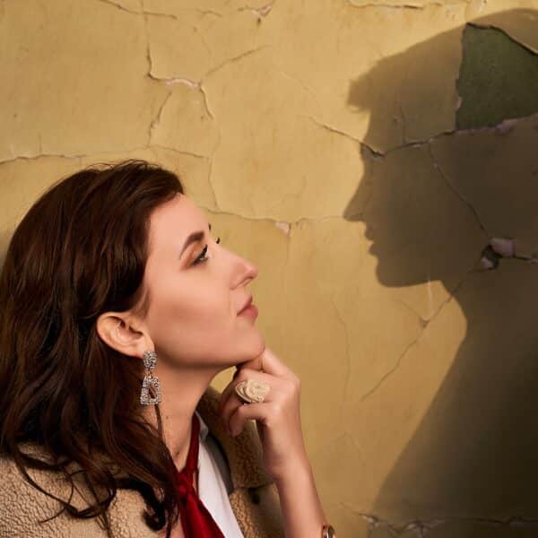 A woman stands against a wall facing a shadow of her ex representing why I do still think about my ex?