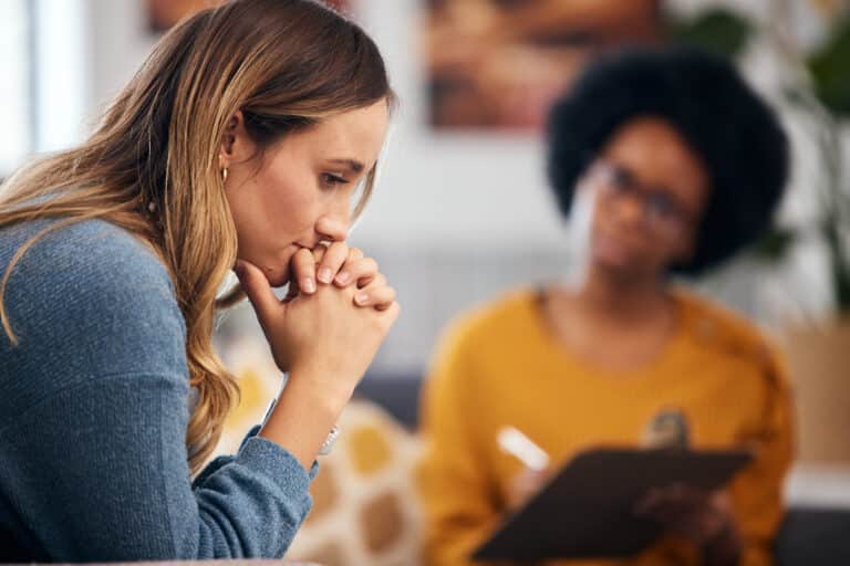 A woman in a therapy session looks sad and confused representing When Therapy For Breakups Backfires (And What To Do Instead)