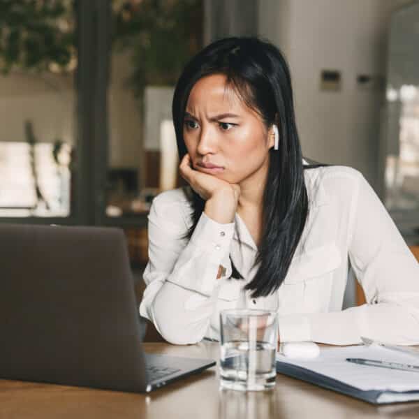 A therapist sits at her desk looking appalled at job postings representing Are Mental Health Coaches Replacing Therapists?!