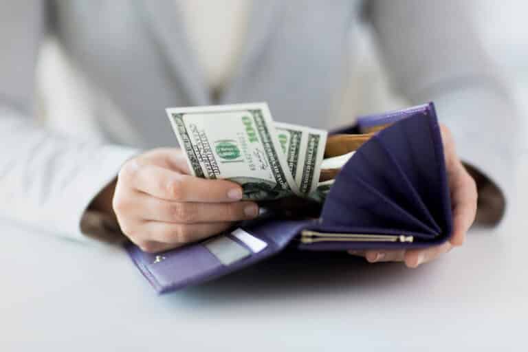 A woman take money out of her wallet representing How to Build a Healthy Relationship With Money