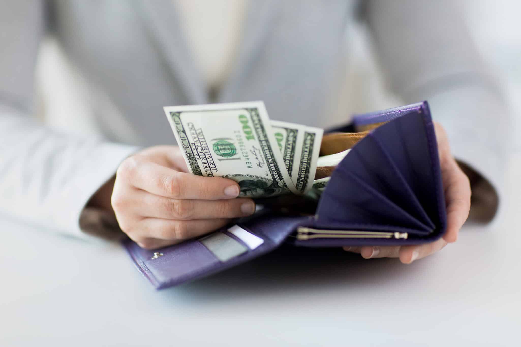 A woman take money out of her wallet representing How to Build a Healthy Relationship With Money