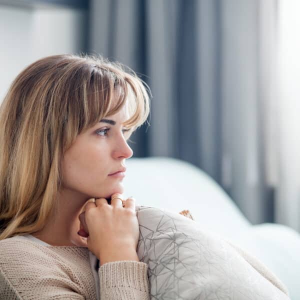 A sad woman sits on her couch after a breakup representing losing yourself in a relationship.